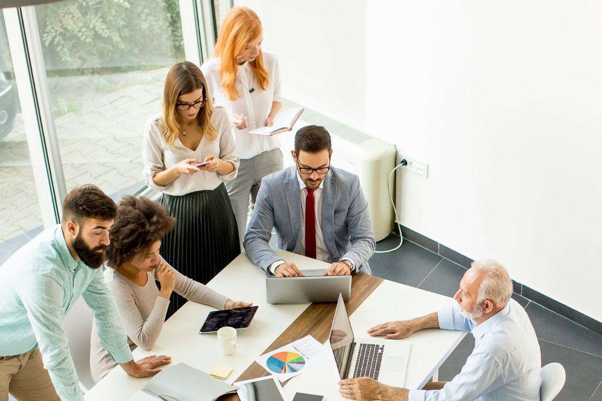 Group of people working as a team in a meeting room, using laptops and taking notes