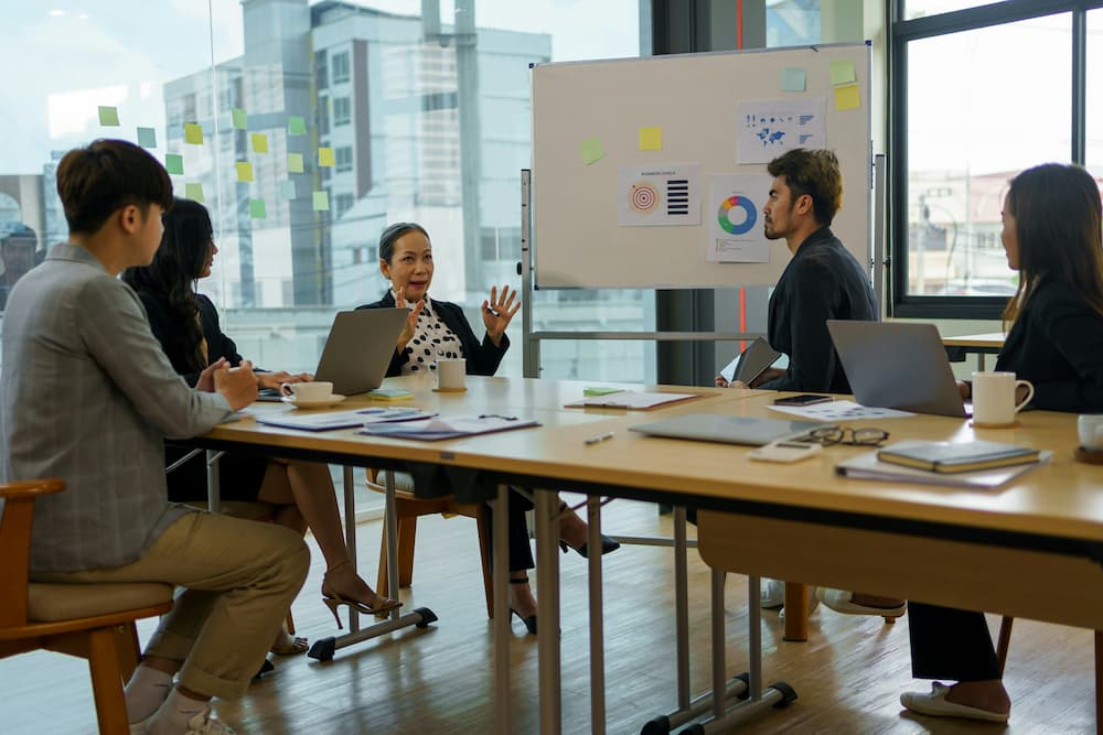 Business meeting with a presentation panel, where participants discuss strategies and analyze charts in a modern and well-lit environment