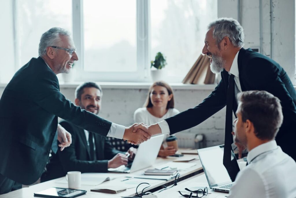Lawyers shaking hands during a meeting, symbolizing collaboration and digital transformation in law firms.