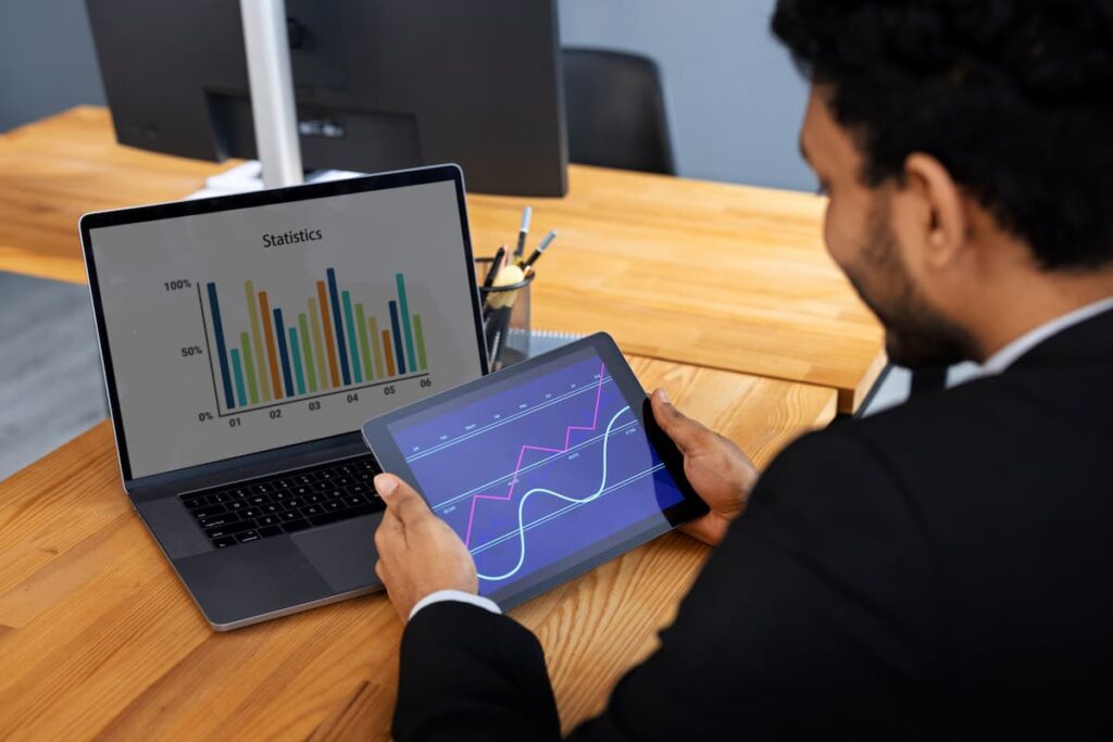 Businessman analyzing graphs on laptop and tablet, illustrating the benefits of seamless financial API integration.