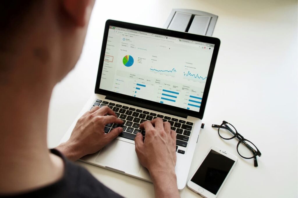 Person analyzing data dashboards on a laptop, exploring predictive analytics vs prescriptive analytics for decision-making.