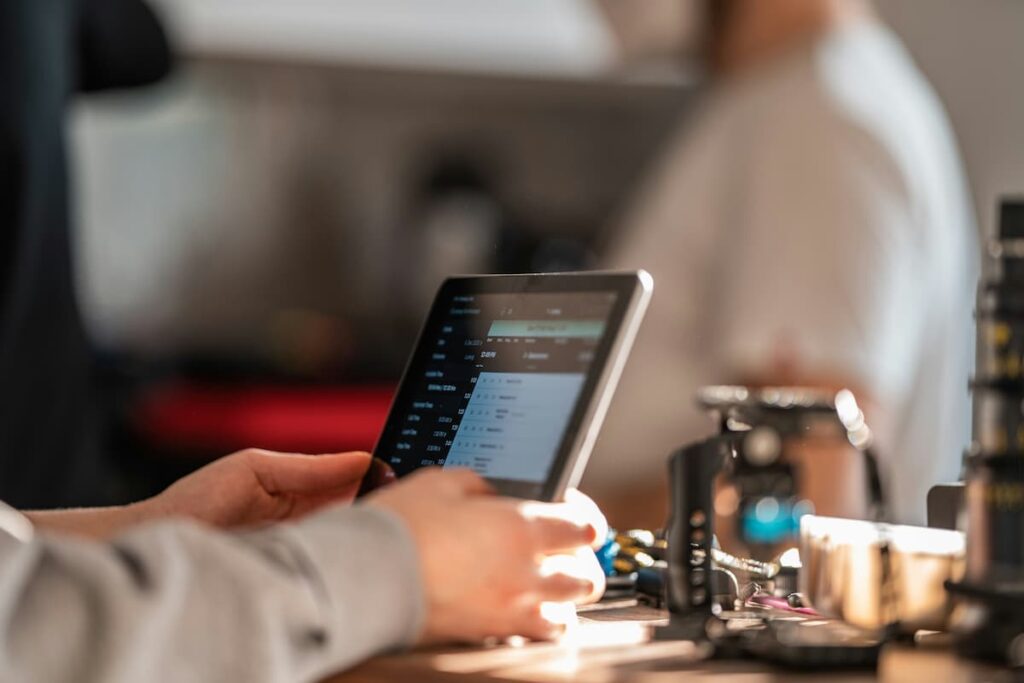 Hands using tablet with dashboard interface, illustrating the use of custom software for manufacturing process control.