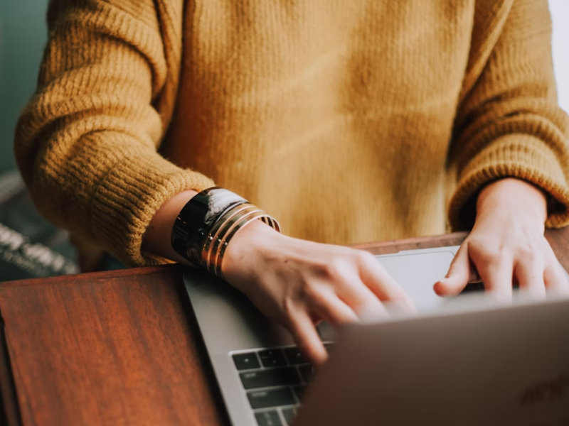 A close-up shot of a person typing on a laptop.